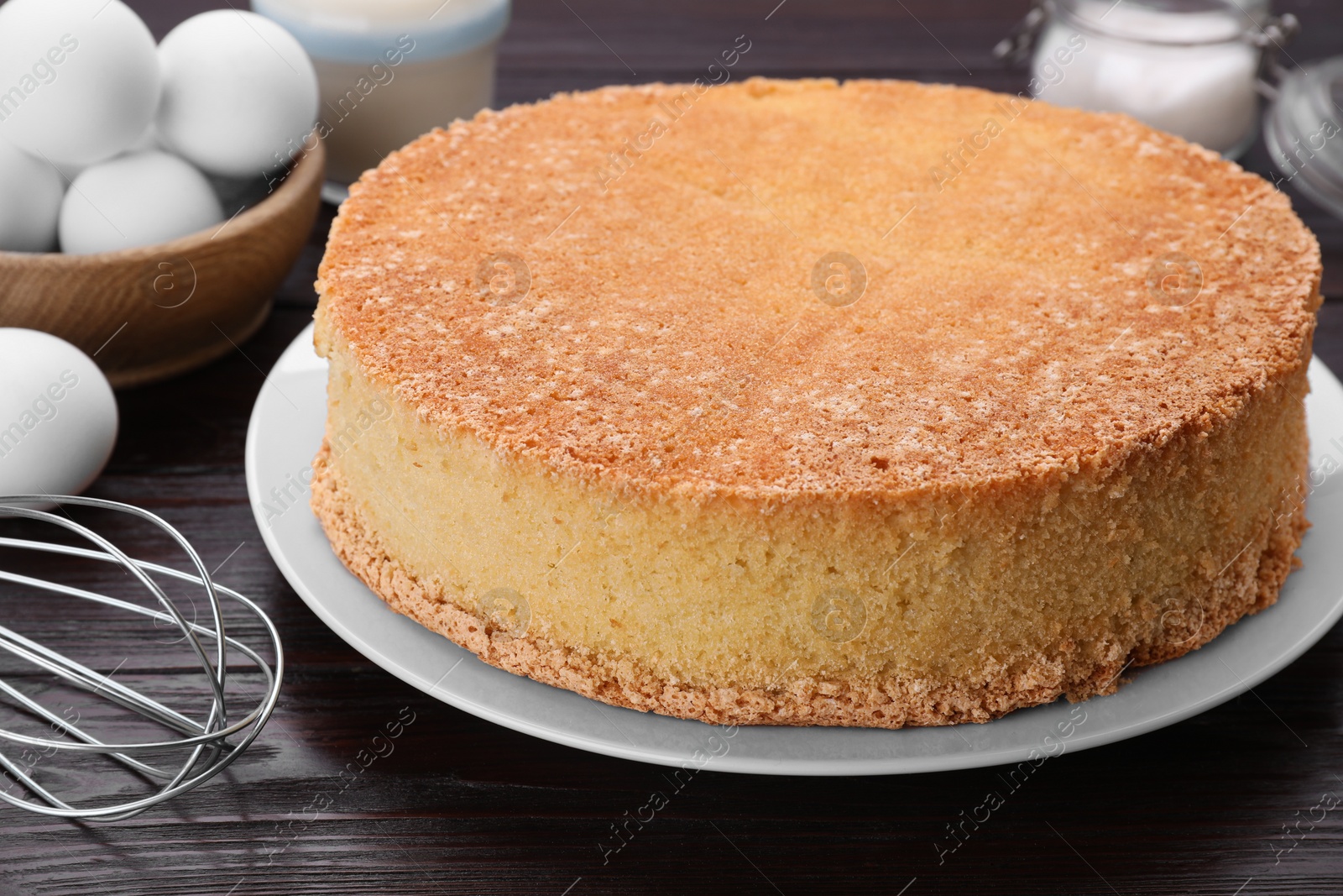 Photo of Plate with delicious sponge cake on dark wooden table, closeup