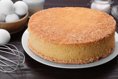 Plate with delicious sponge cake on dark wooden table, closeup