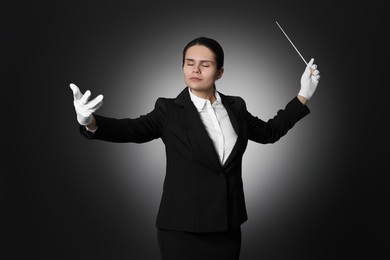 Professional conductor with baton on black background