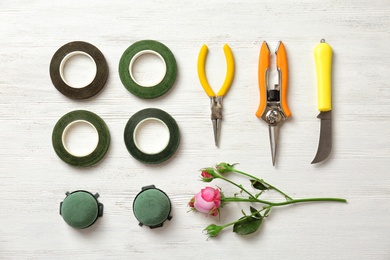 Flat lay composition with florist equipment and flower on wooden background