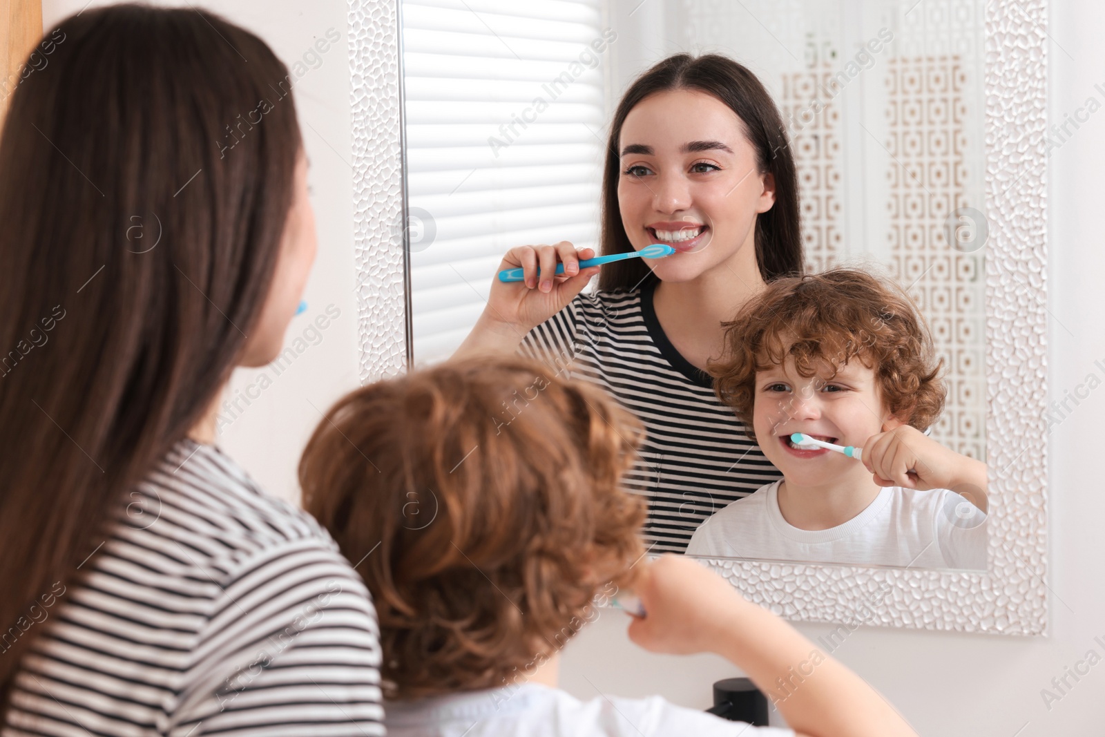 Photo of Mother and her son brushing teeth together near mirror in bathroom
