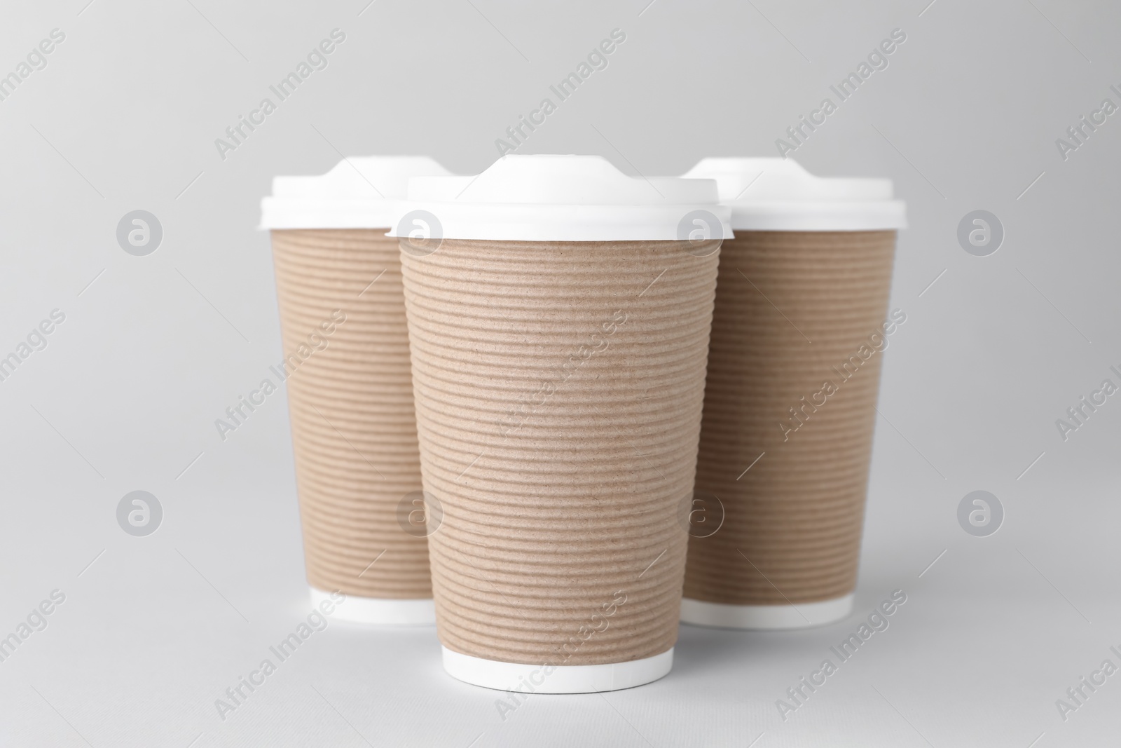 Photo of Paper cups with white lids on light grey background. Coffee to go