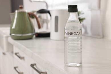 Photo of Cleaning electric kettle. Bottle of vinegar on countertop in kitchen