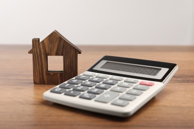 Photo of Mortgage concept. House model and calculator on wooden table