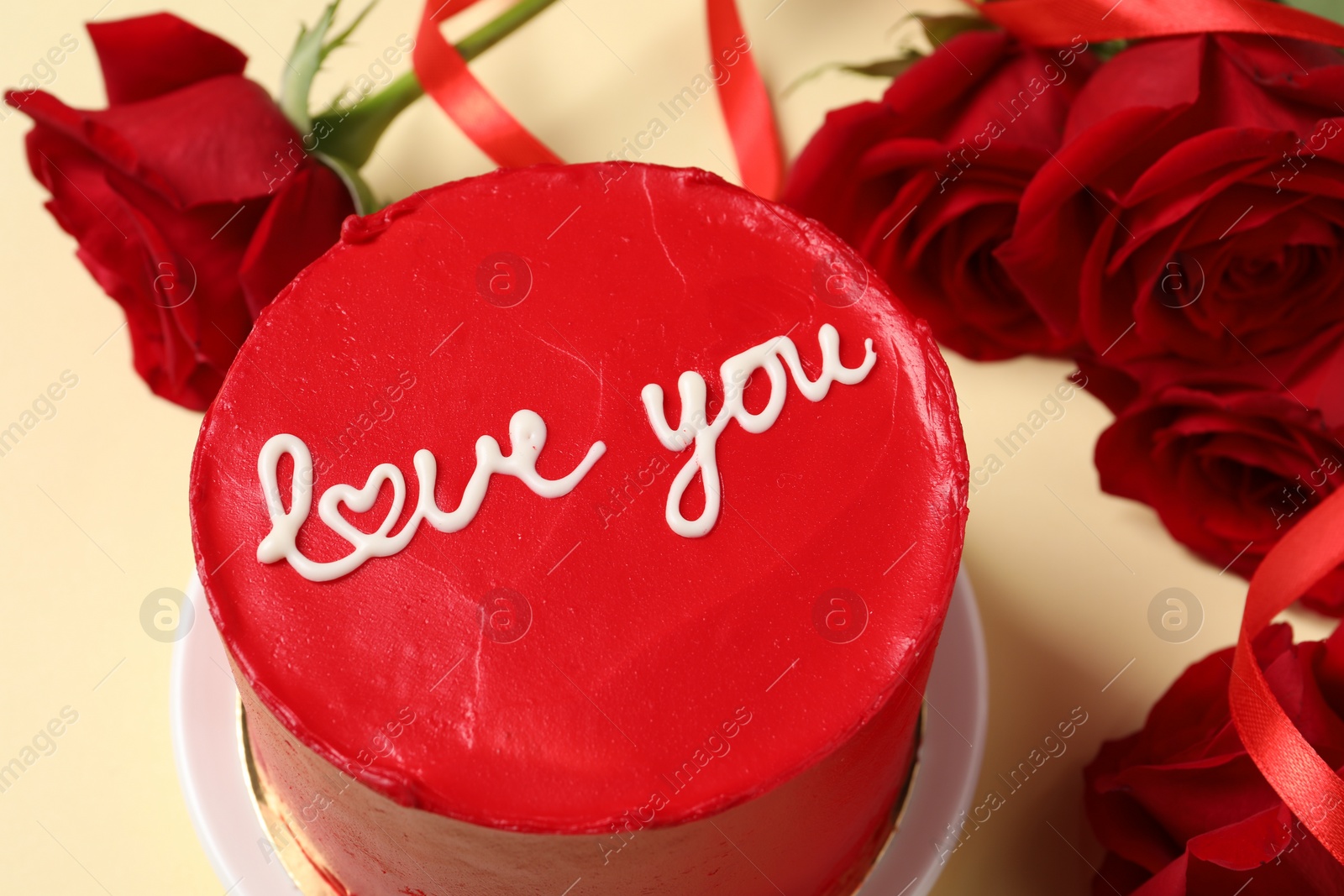 Photo of Bento cake with text Love You and red roses on beige table, closeup. St. Valentine's day surprise