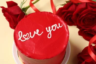 Photo of Bento cake with text Love You and red roses on beige table, closeup. St. Valentine's day surprise