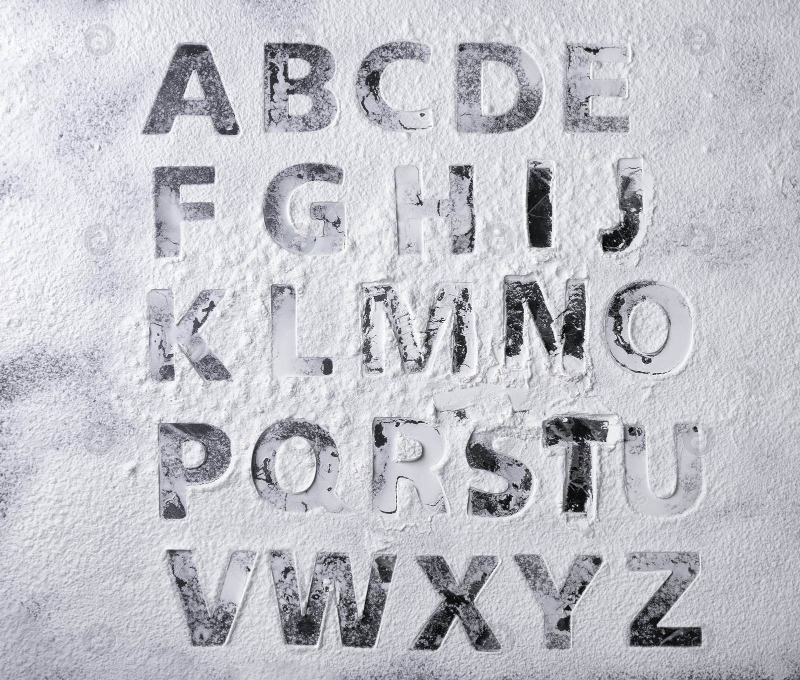 Photo of Silhouettes of alphabet letters on scattered flour