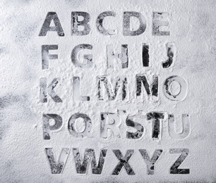 Photo of Silhouettes of alphabet letters on scattered flour