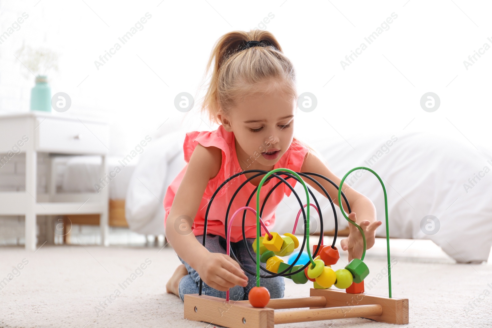 Photo of Cute child playing with bead maze on floor at home