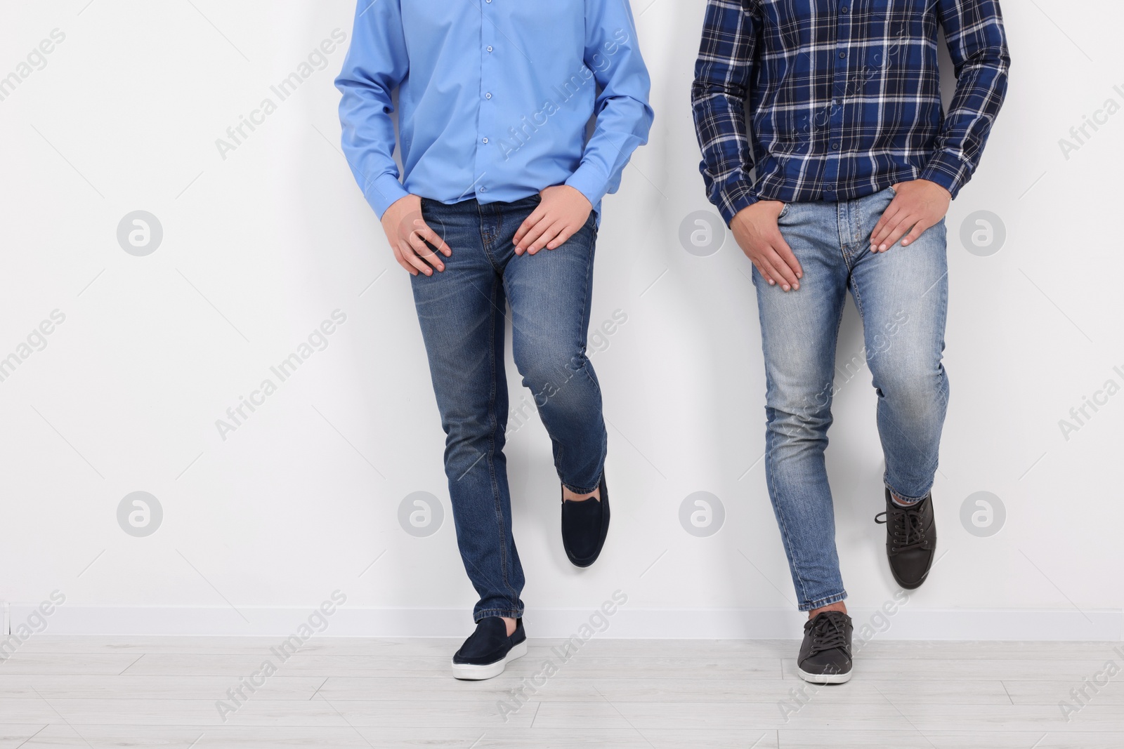 Photo of Men in stylish jeans near white wall indoors, closeup