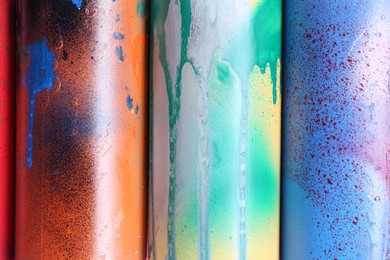 Different spray paint cans as background, top view