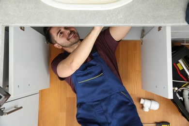 Male plumber repairing kitchen sink, top view