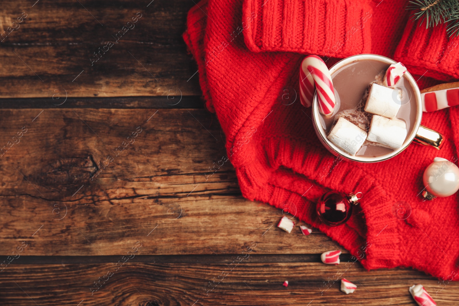 Photo of Flat lay composition with cup of tasty cocoa, candy cane and Christmas decor on wooden table, flat lay. Space for text