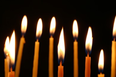 Photo of Many burning church candles on dark background, closeup