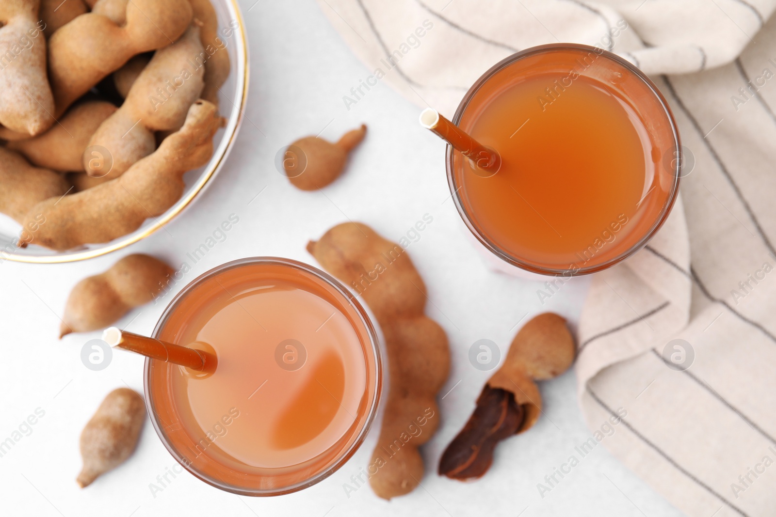 Photo of Tamarind juice and fresh fruits on white table, flat lay