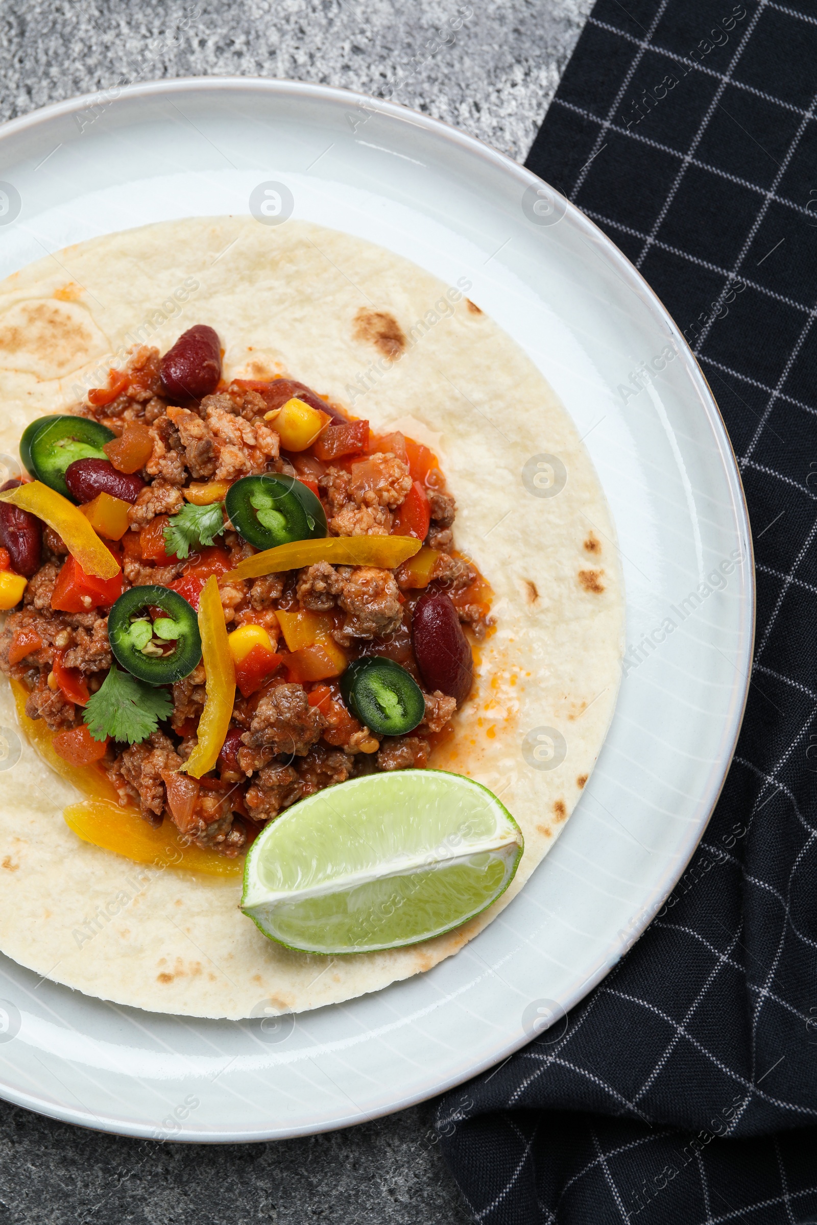 Photo of Tasty chili con carne with tortilla on grey table, flat lay