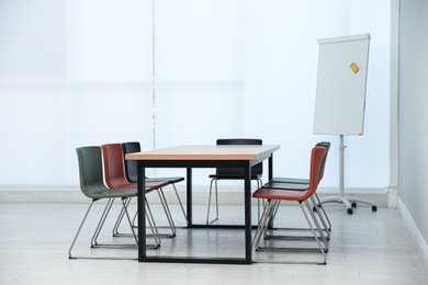 Photo of Conference room interior with wooden table and flipchart