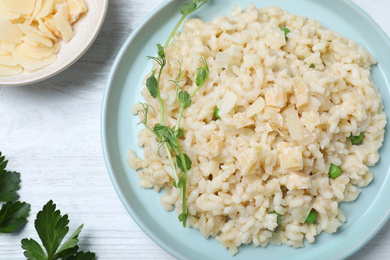 Photo of Delicious risotto with cheese on white wooden table, flat lay