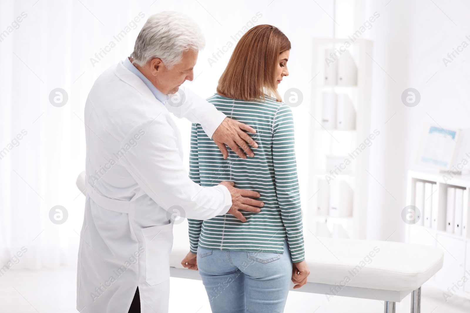 Photo of Chiropractor examining patient with back pain in clinic