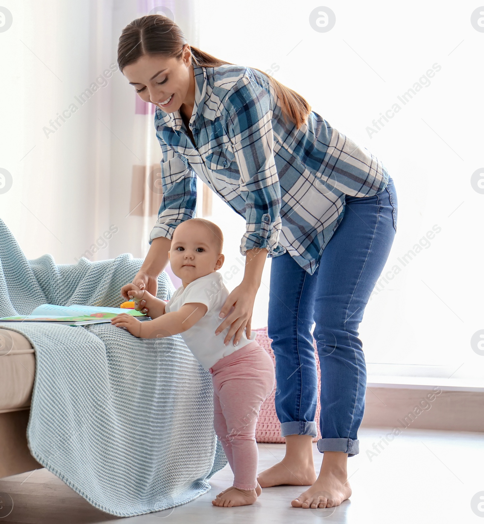 Photo of Baby learning to walk with mother's help at home