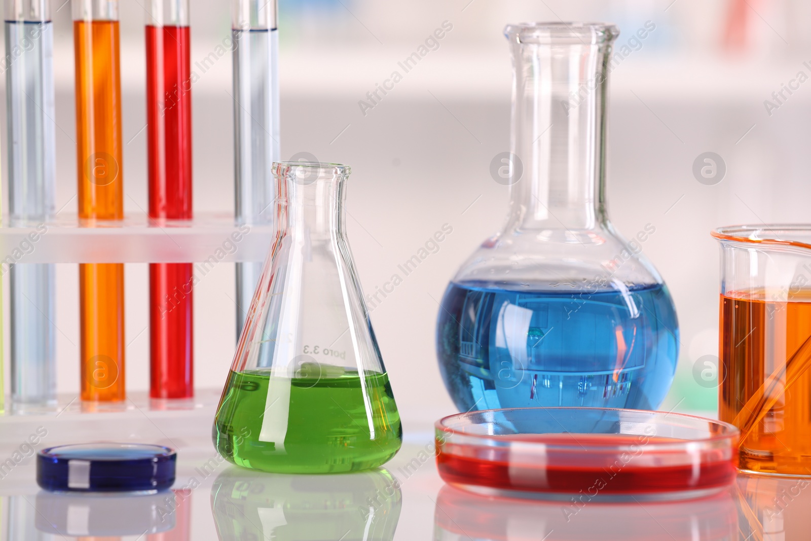 Photo of Laboratory analysis. Different glassware with liquids on white table against blurred background, closeup
