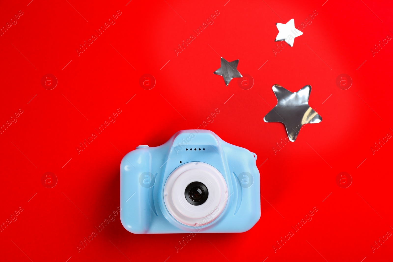Photo of Toy camera and stars on red background, top view