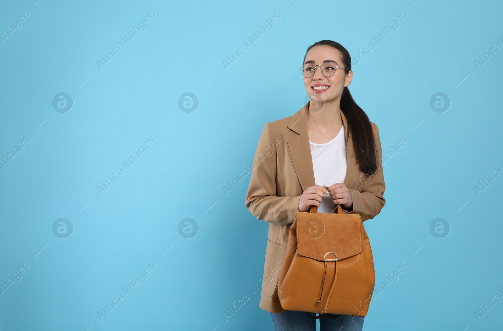 Photo of Beautiful young woman with stylish leather backpack on turquoise background. Space for text