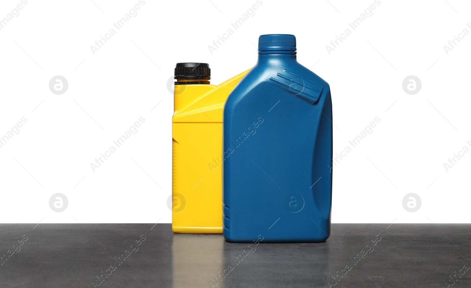 Photo of Motor oil in different containers on grey table against white background