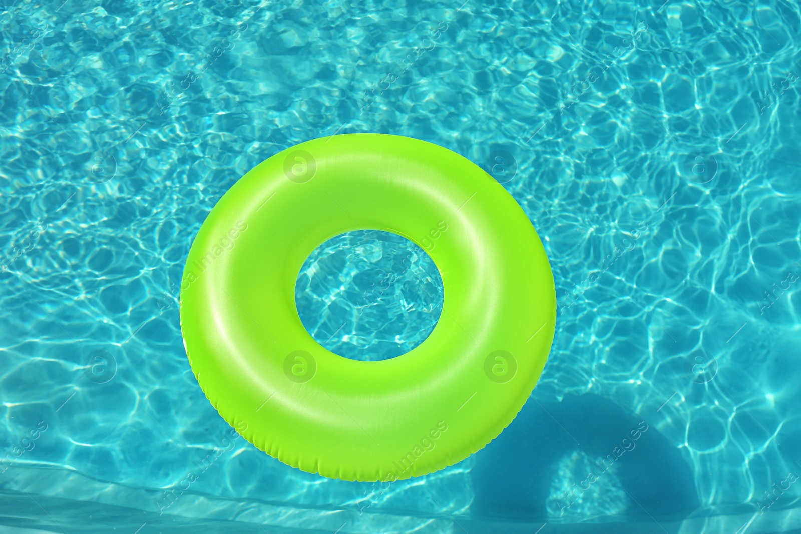 Photo of Bright inflatable ring floating in swimming pool on sunny day, above view