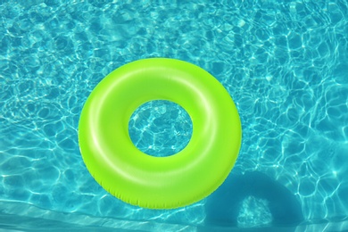 Photo of Bright inflatable ring floating in swimming pool on sunny day, above view