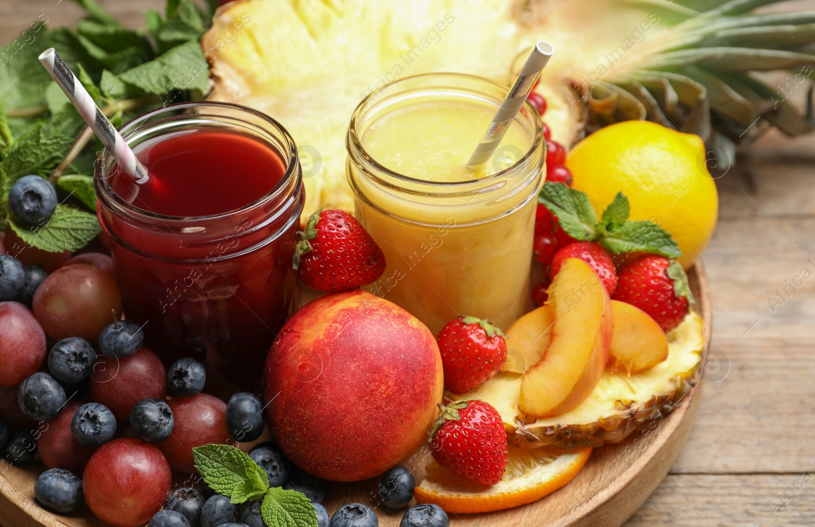 Photo of Delicious colorful juices in glasses and fresh ingredients on wooden table