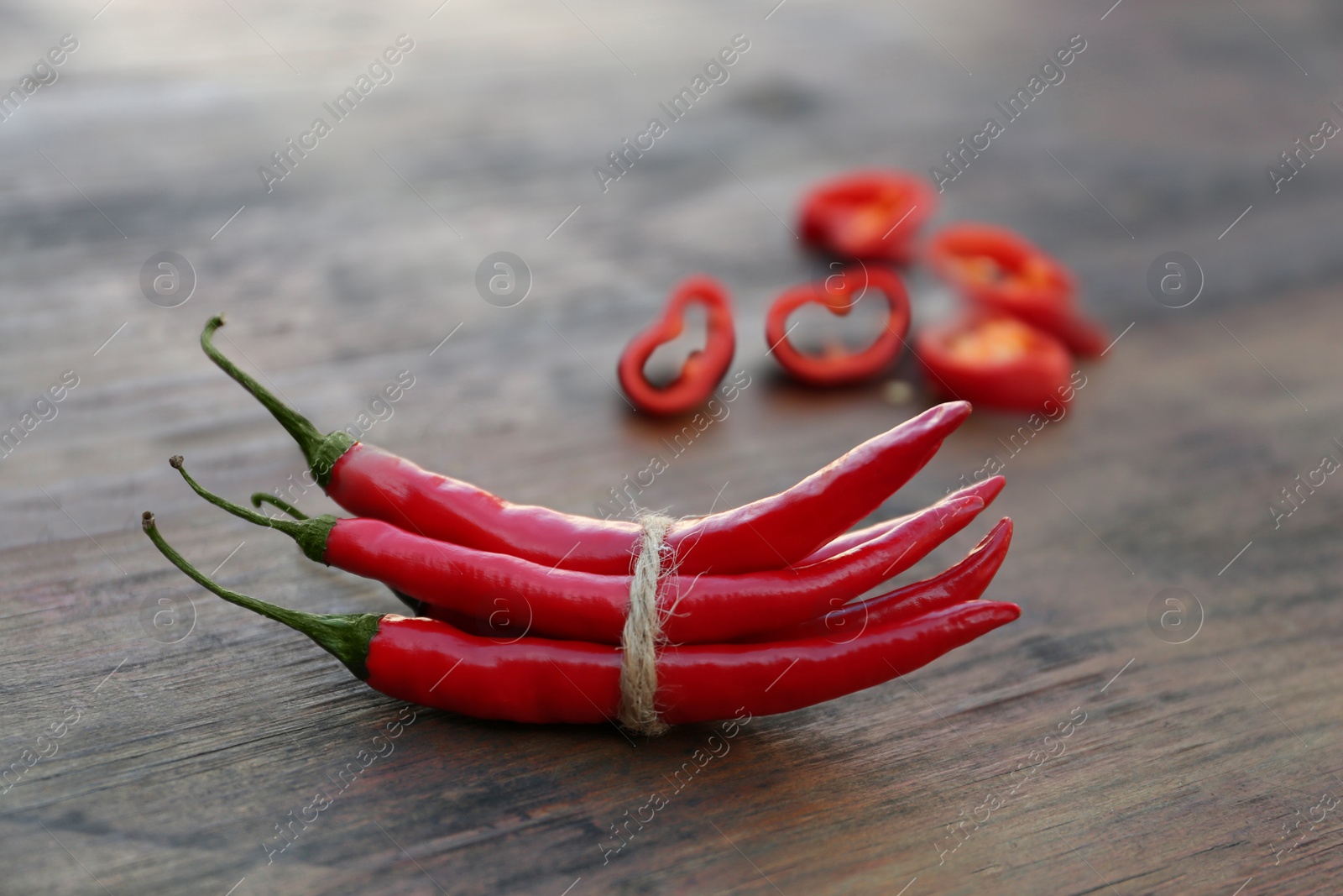 Photo of Whole and cut red chili peppers on wooden table