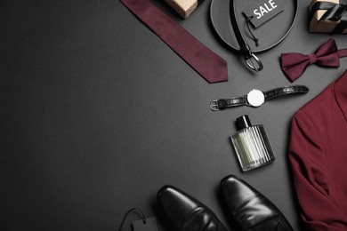 Photo of Flat lay composition with men's clothes and accessories on dark background, space for text. Black Friday sale