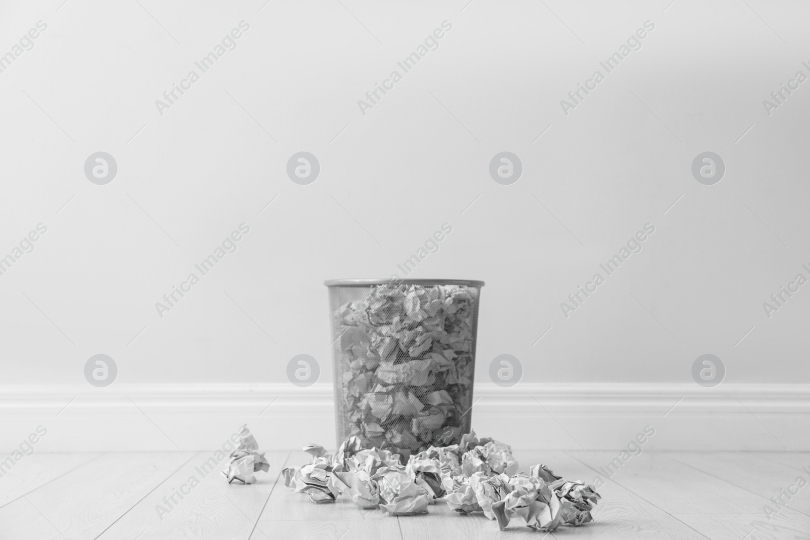 Photo of Metal bin and crumpled paper against light wall