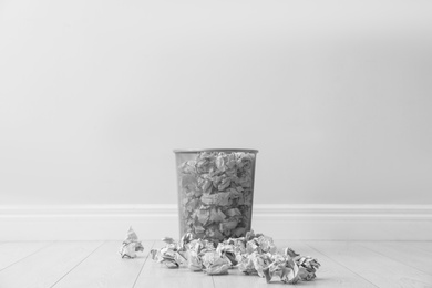 Photo of Metal bin and crumpled paper against light wall