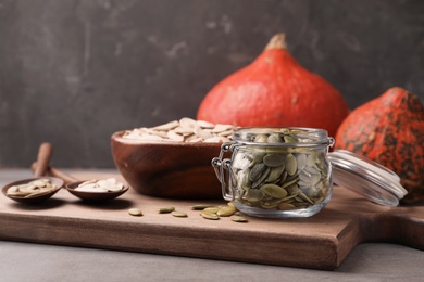 Photo of Shelled raw pumpkin seeds in jar on wooden board