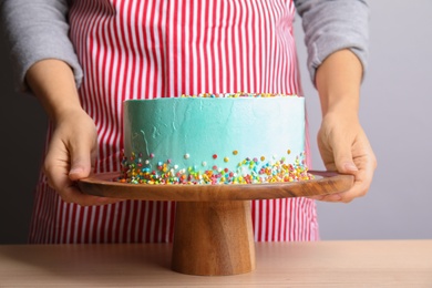 Woman with fresh delicious birthday cake on stand, closeup