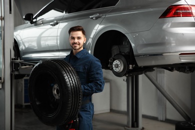 Photo of Technician with car wheel in automobile repair shop