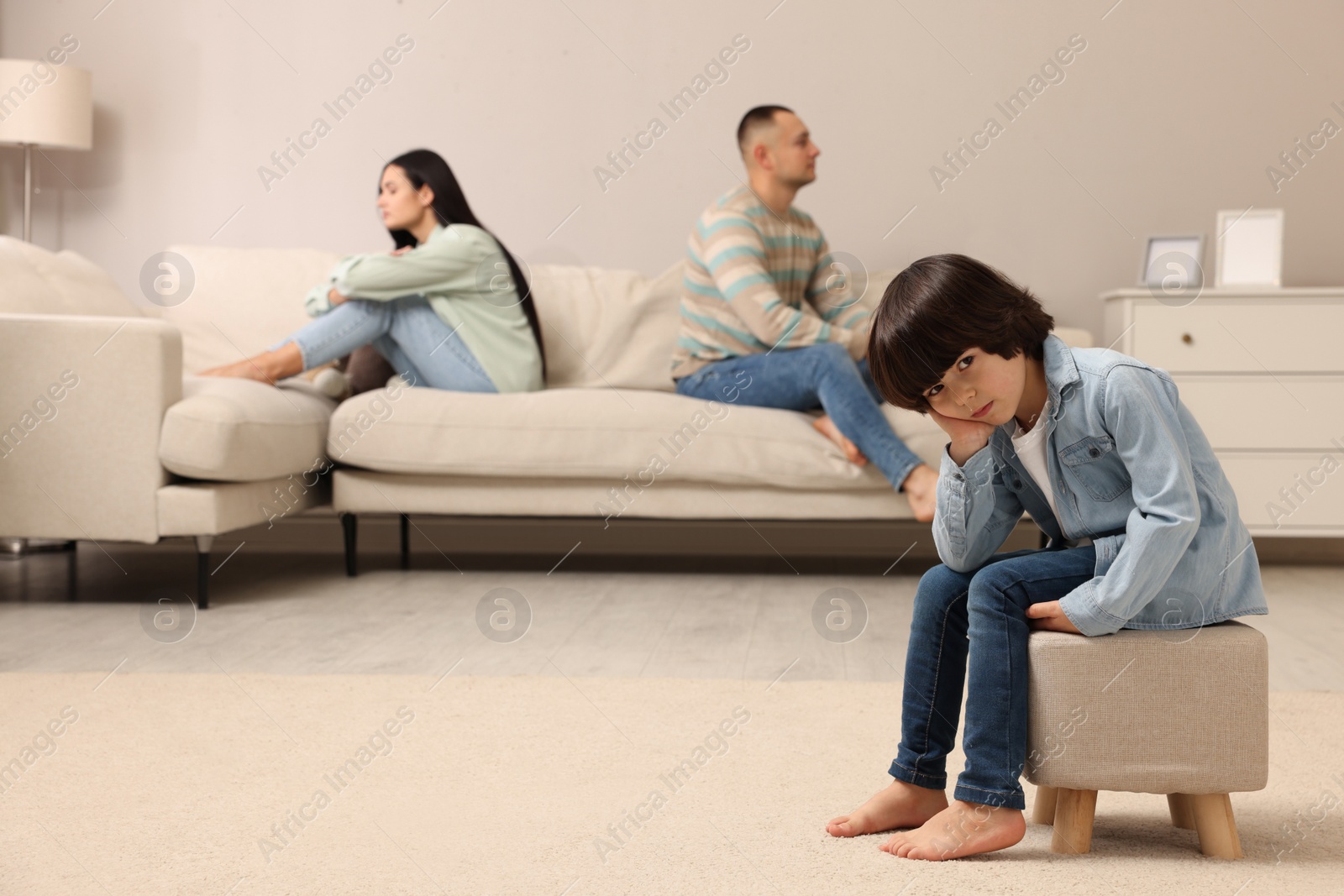 Photo of Sad couple with relationship problems at home, focus on their upset child