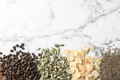 Photo of Many different spices on white marble background, top view. Space for text