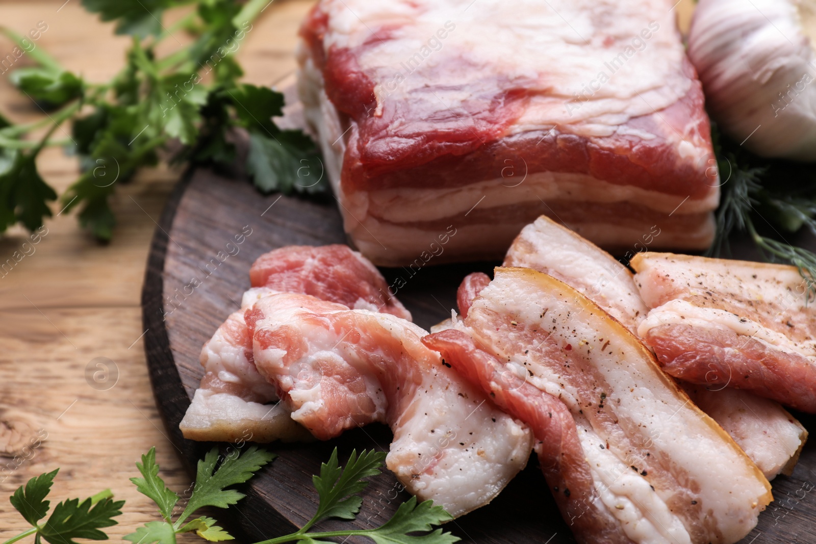 Photo of Pork fatback and fresh parsley on wooden table, closeup