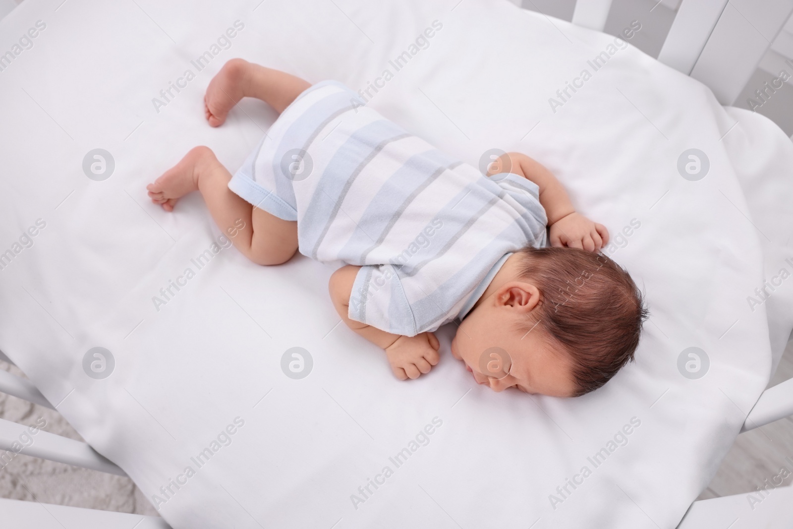 Photo of Cute newborn baby sleeping in crib, top view. Bedtime