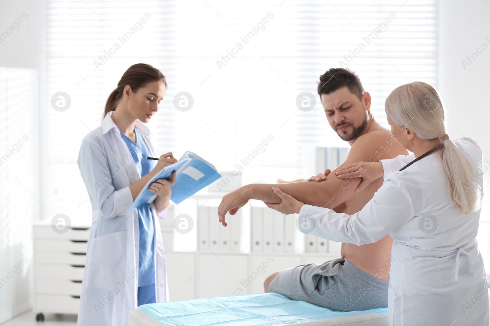 Photo of Female orthopedist examining patient's arm in clinic