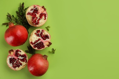 Flat lay composition with ripe pomegranates on green background. Space for text