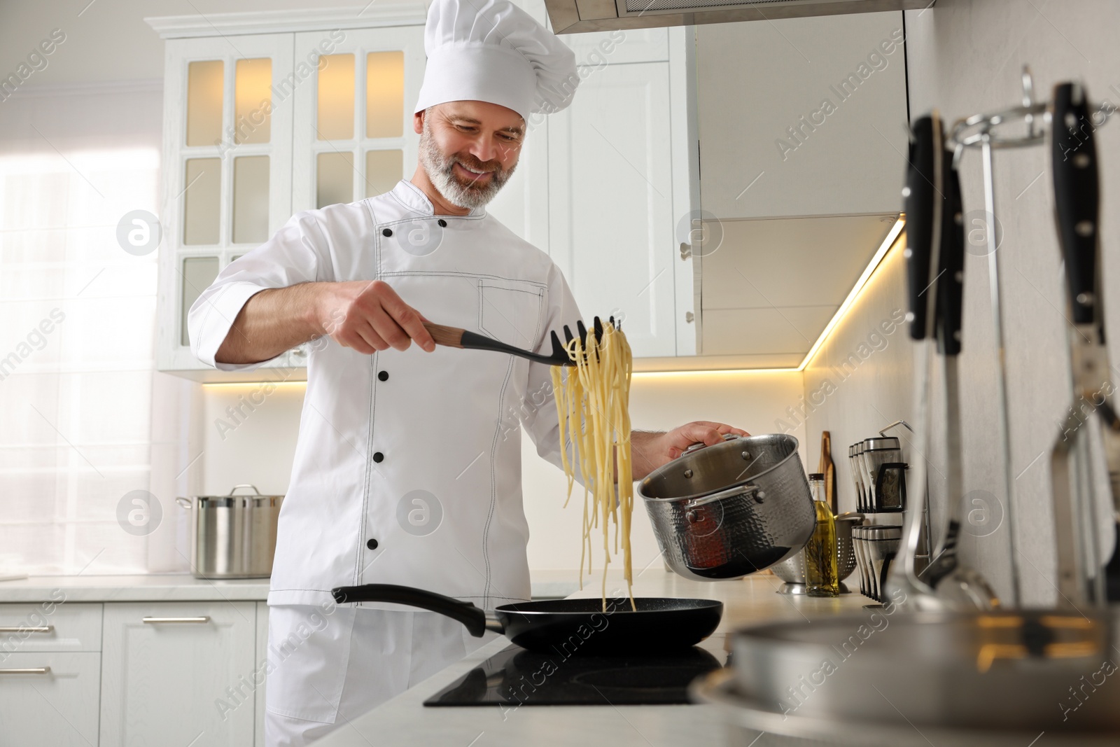 Photo of Professional chef cooking delicious pasta in kitchen low angle view