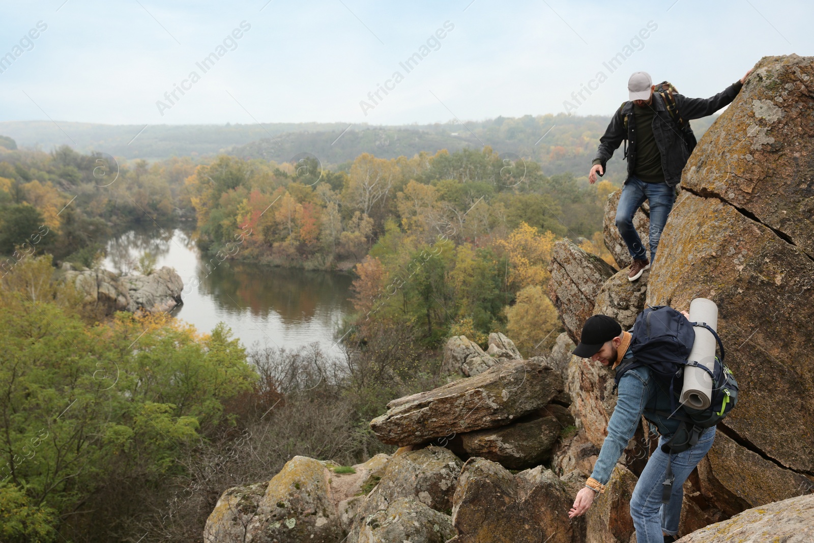 Photo of Hikers with backpacks climbing up mountain on autumn day