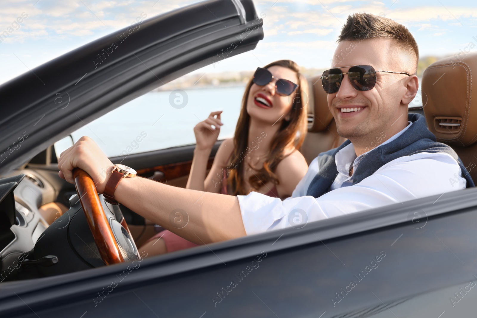 Photo of Stylish couple driving luxury convertible car outdoors