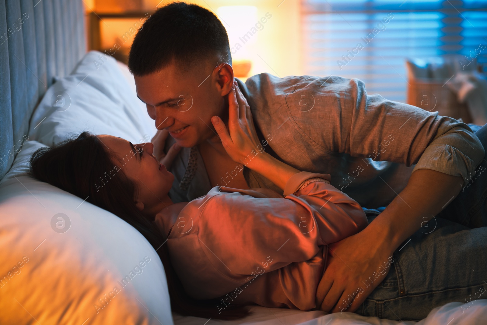 Photo of Affectionate couple enjoying each other on bed at night