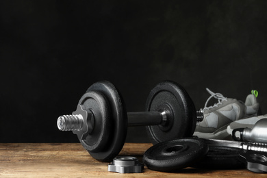 Photo of Gym equipment and accessories on wooden floor against dark background