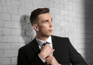 Photo of Portrait of young man with beautiful hair on brick wall background